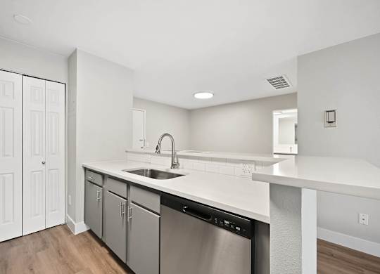 A modern kitchen with white cabinets and a stainless steel dishwasher. at The Lex At Lowry, Denver, Colorado