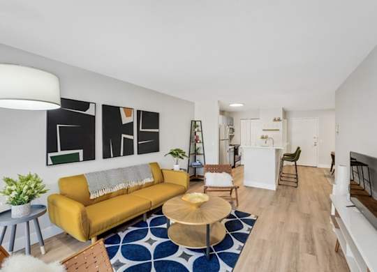A living room with a yellow couch and a blue and white rug. at The Lex At Lowry, Denver, CO