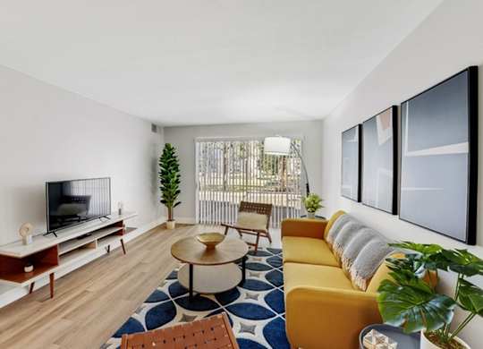 A living room with a television, a yellow couch, and a blue and white rug. at The Lex At Lowry, Denver, CO, 80224