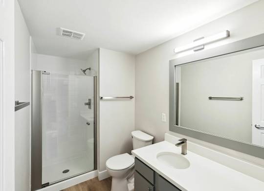 A white bathroom with a toilet, sink, and shower. at The Lex At Lowry, Denver, 80224
