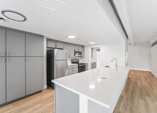 A modern kitchen with a white countertop and wooden flooring. at The Lex At Lowry, Denver, Colorado