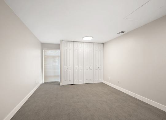 A room with a grey carpet and white walls with a white wardrobe. at The Lex At Lowry, Denver