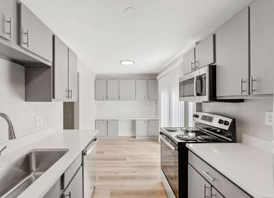 A modern kitchen with stainless steel appliances and white cabinets. at The Lex At Lowry, Denver