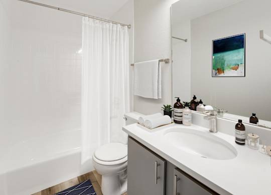 A white bathroom with a toilet, sink, and shower. at The Lex At Lowry, Denver