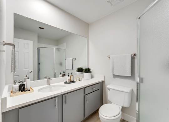 A white toilet sits next to a sink in a bathroom. at The Lex At Lowry, Denver, 80224