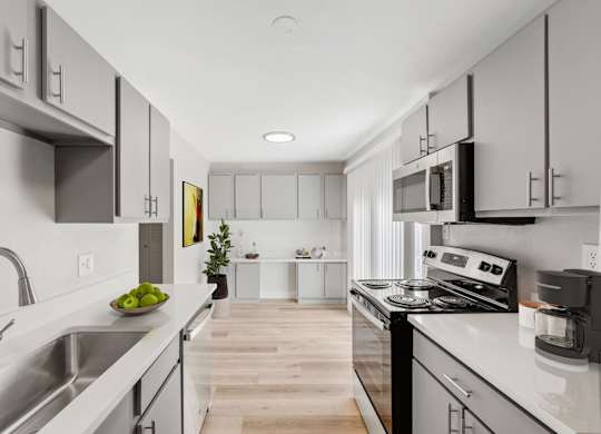 A modern kitchen with stainless steel appliances and white cabinets. at The Lex At Lowry, Denver