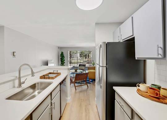 A modern kitchen with a black refrigerator and wooden floors. at The Lex At Lowry, Colorado, 80224