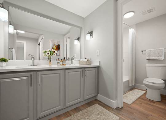 A bathroom with a white toilet and grey cabinets. at The Lex At Lowry, Denver, Colorado