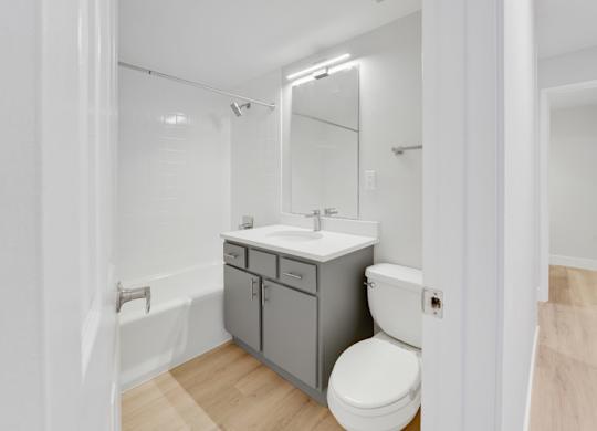A white toilet sits next to a sink in a small bathroom. at The Lex At Lowry, Colorado