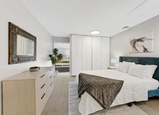 A bedroom with a large bed and a mirror on the wall. at The Lex At Lowry, Denver, 80224