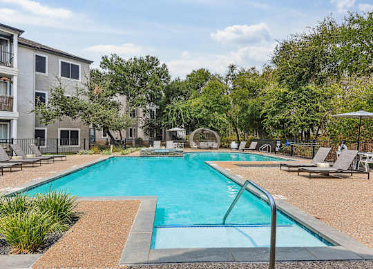 A swimming pool surrounded by lounge chairs and trees.at Onyx183, Texas  