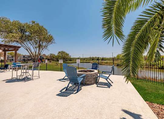 A concrete patio with blue chairs and a table.