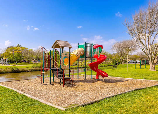 A playground with a red slide and a yellow slide.