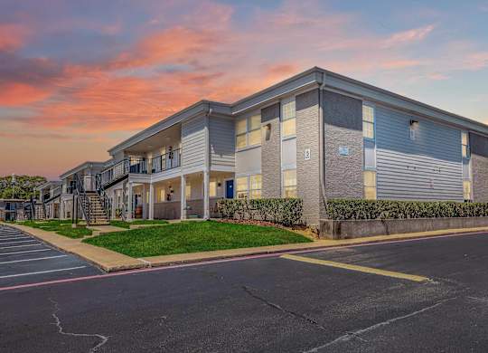 A modern apartment building with a parking lot in front.