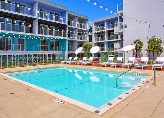 A large swimming pool in front of a multi-story apartment building.at Prizma, Los Angeles, CA 90038  