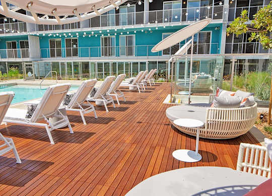 A poolside deck with sun loungers and a table.at Prizma, Los Angeles, CA  