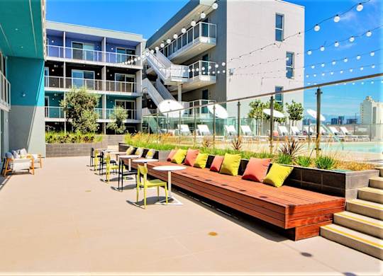 A patio with a long bench and tables is surrounded by buildings.at Prizma, California, 90038