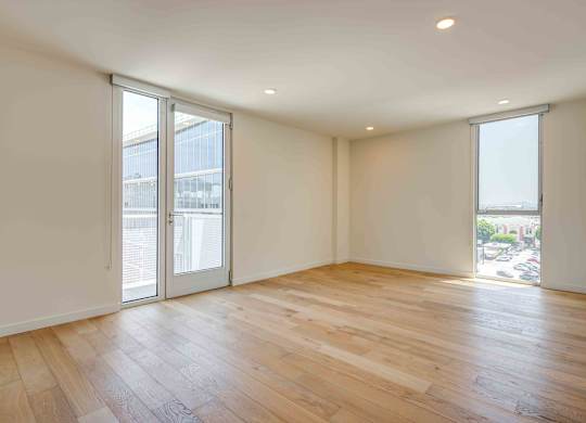 A room with wooden flooring and sliding glass doors.at Prizma, Los Angeles, CA  