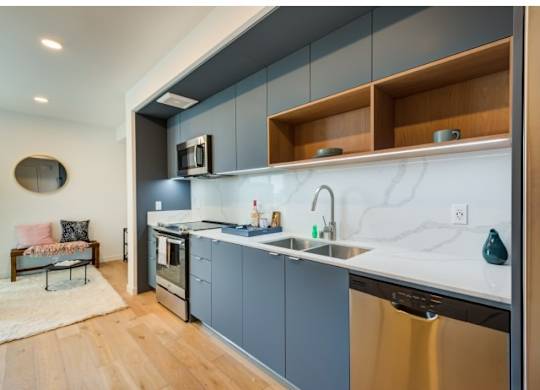 A modern kitchen with a stainless steel dishwasher and a marble backsplash.at Prizma, Los Angeles, CA  