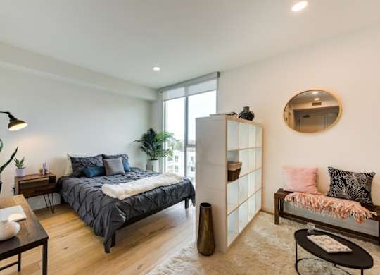 A bedroom with a bed, a bench, and a mirror on the wall.at Prizma, California, 90038