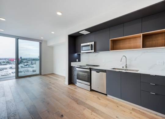A modern kitchen with a large window overlooking a cityscape.at Prizma, Los Angeles, 90038  