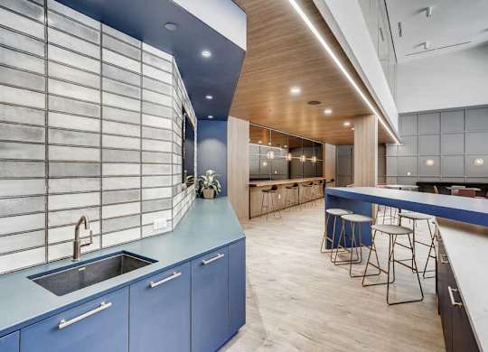 A modern kitchen with blue cabinets and a wooden ceiling.