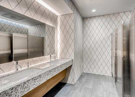 A bathroom with a marble countertop and a diamond patterned wall.