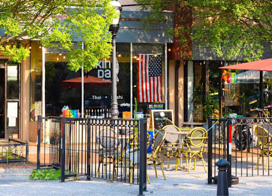 A restaurant with tables and chairs is surrounded by a black fence.at The Vale at the Parks, Washington District of Columbia  