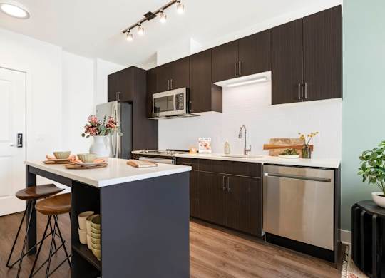 A kitchen with a white counter top and brown cabinets.at The Vale at the Parks, Washington, DC  