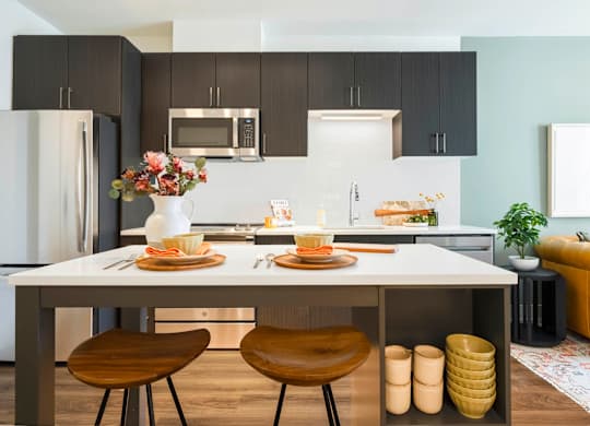A modern kitchen with a dining table set for two.at The Vale at the Parks, Washington, DC 20012  