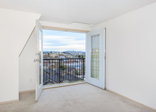 A view of a city from a balcony through a glass door.