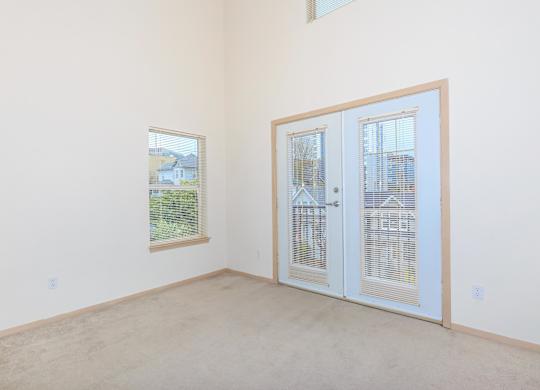 A room with a white door and a window with a view of a house.