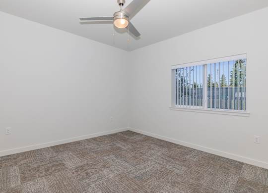 A room with a ceiling fan and a window with blinds.