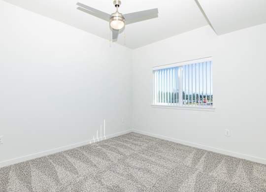 A room with a ceiling fan and a window with blinds.