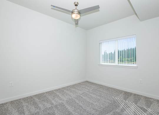 A room with a ceiling fan and a window with blinds.