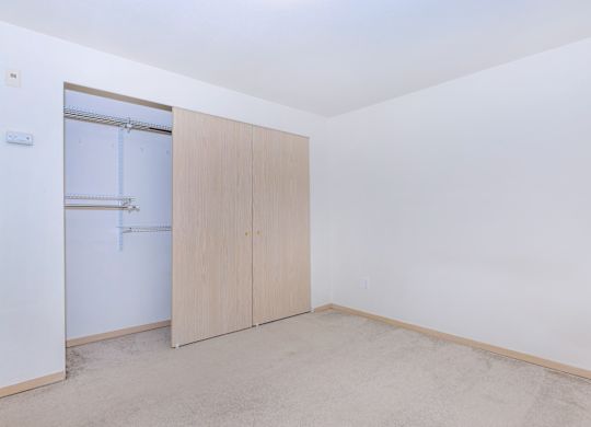 A room with a white wall and a brown floor with a wardrobe.
