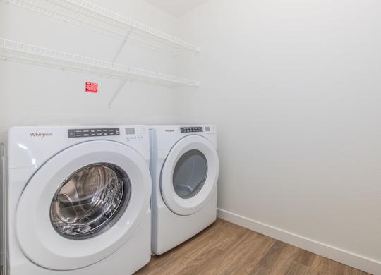 Two white Whirlpool washing machines in a laundry room.