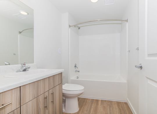 A white bathroom with a toilet, sink, and bathtub.