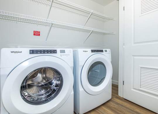 Two white Whirlpool washing machines in a laundry room.