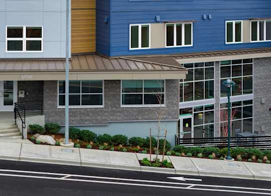 A blue building with a brown awning and a tree in front of it.