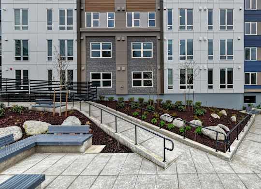 A modern courtyard with a bench and a planter box.