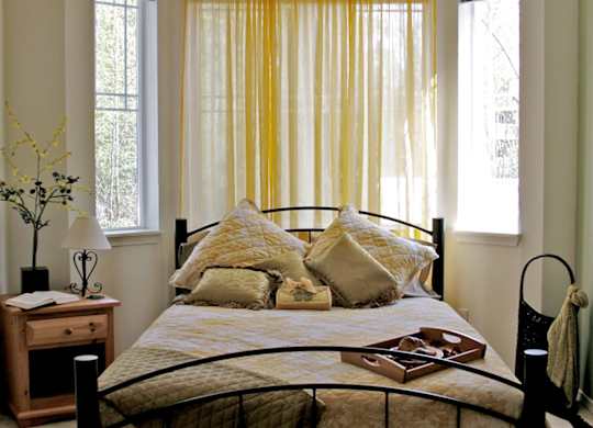 A bed with a yellow comforter and a black headboard.