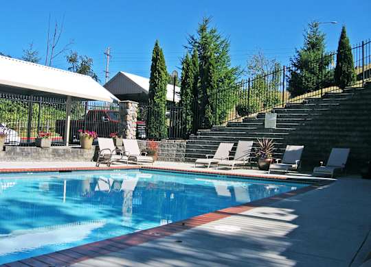 A pool with a red and blue border and white lounge chairs.