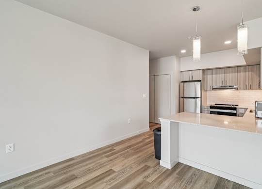 A kitchen with a white counter and wooden floors.