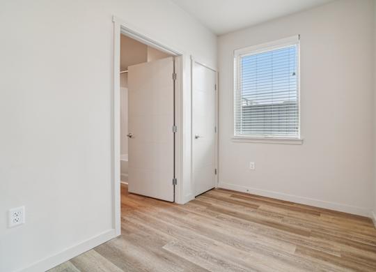 A room with a white door and a window with blinds.