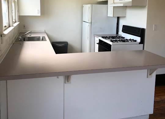 A kitchen with white cabinets and a stove top oven.