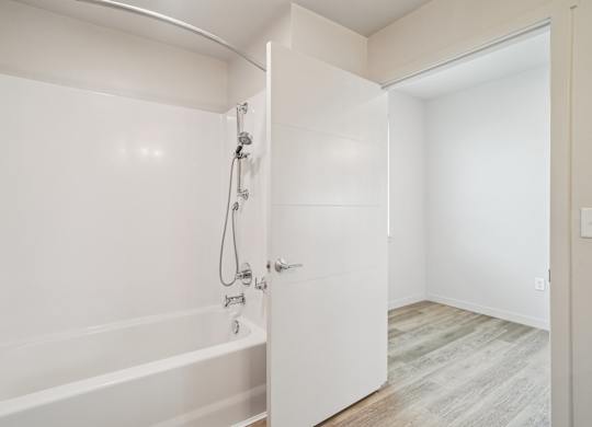 A white bathroom with a tub and a door.