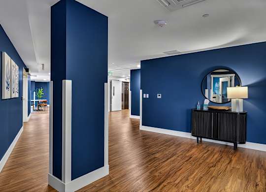A long hallway with a blue wall and a mirror on the wall.