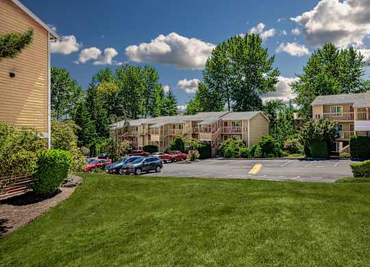 A sunny day at the apartment complex with cars parked in the parking lot.