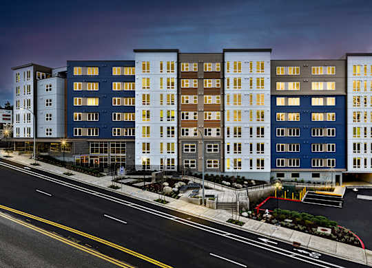 A modern apartment building with a parking lot in front.